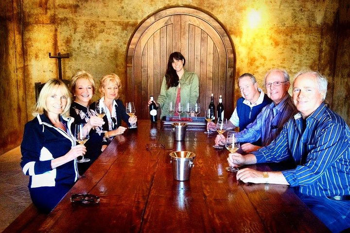 Group of people at a wooden table with wine glasses in a rustic room.