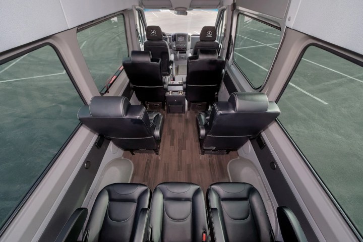 Interior of a van with leather seats arranged in two rows facing forward.