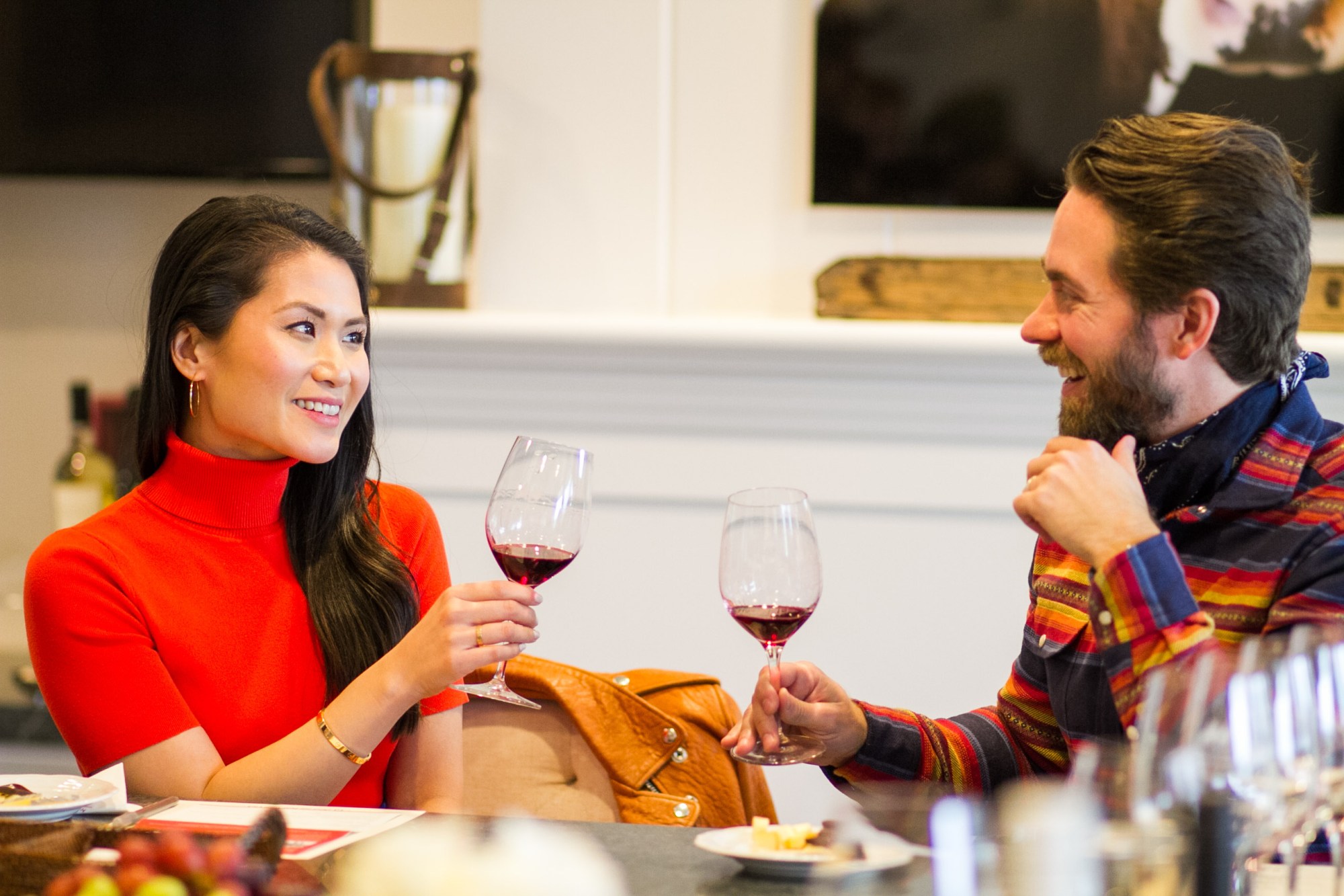 StephanieAndrewWise_SustinableVineWinetours_HappyCanyon2_PhotoByCeciliaRosell-2 Two people smiling and toasting with red wine glasses indoors.