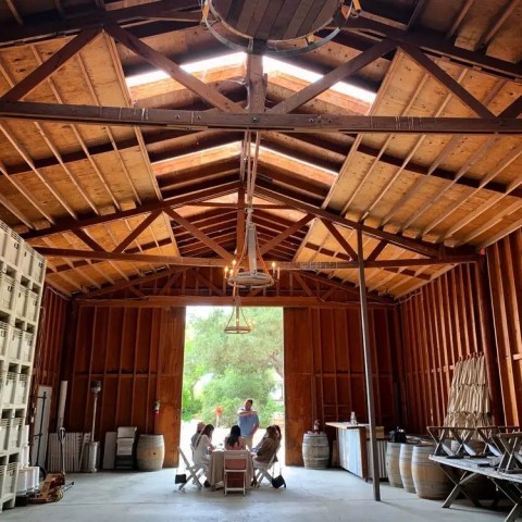 Interior of a wooden barn with a group seated at a table near the entrance.