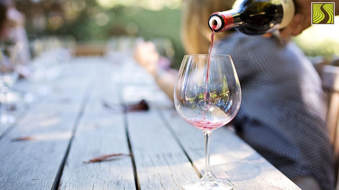 things-to-do-in-montecito-santa-barbara Red wine being poured into a glass on an outdoor table.