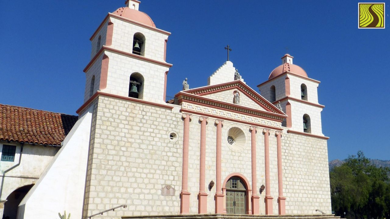 Historic mission-style church with twin bell towers under a clear blue sky.