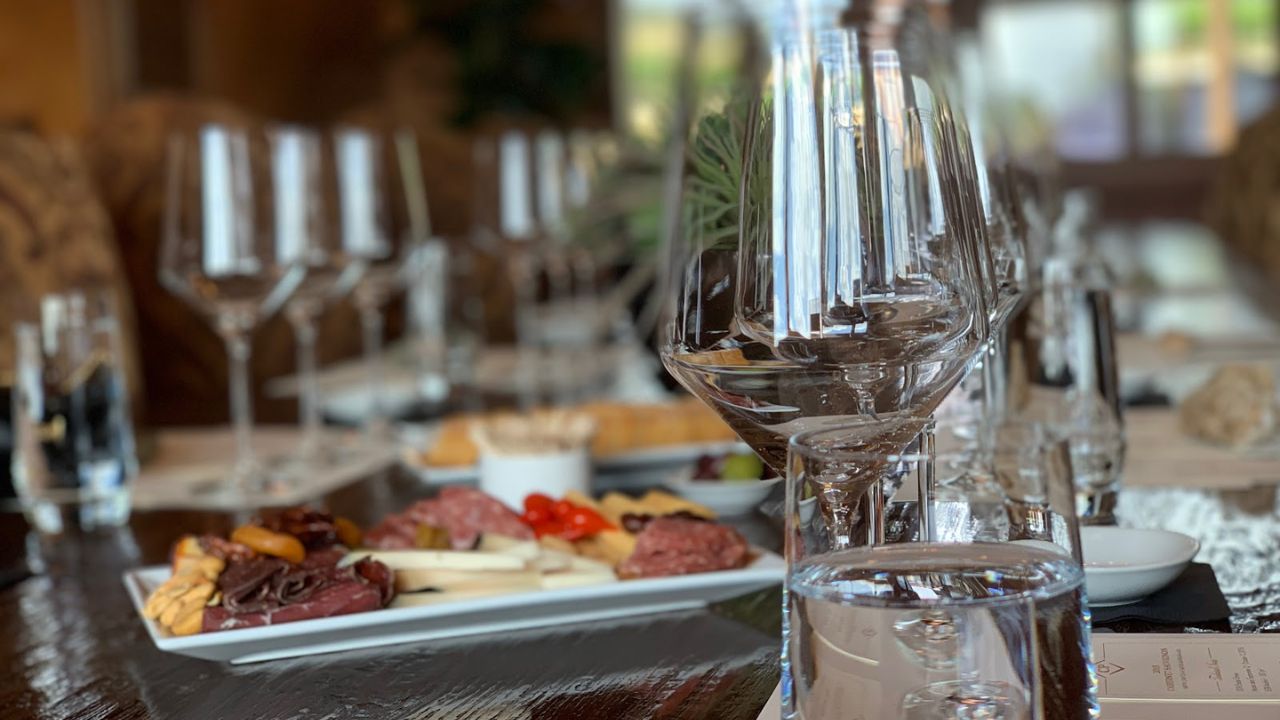 Close-up of table with wine glasses, plates of appetizers, and water glasses.