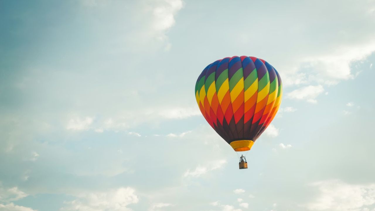 Colorful hot air balloon floating against a clear sky backdrop.
