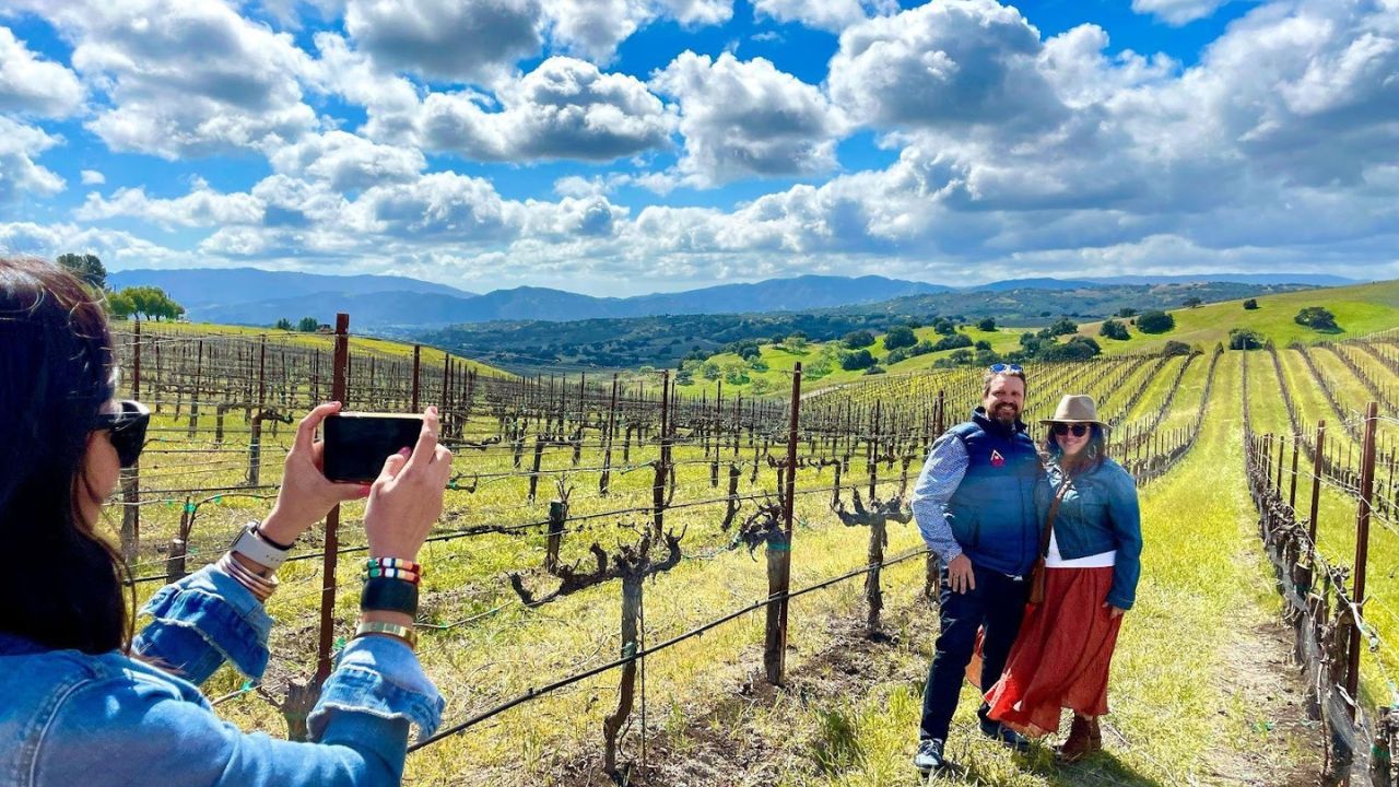 Couple posing in vineyard during wine tour with scenic hills.