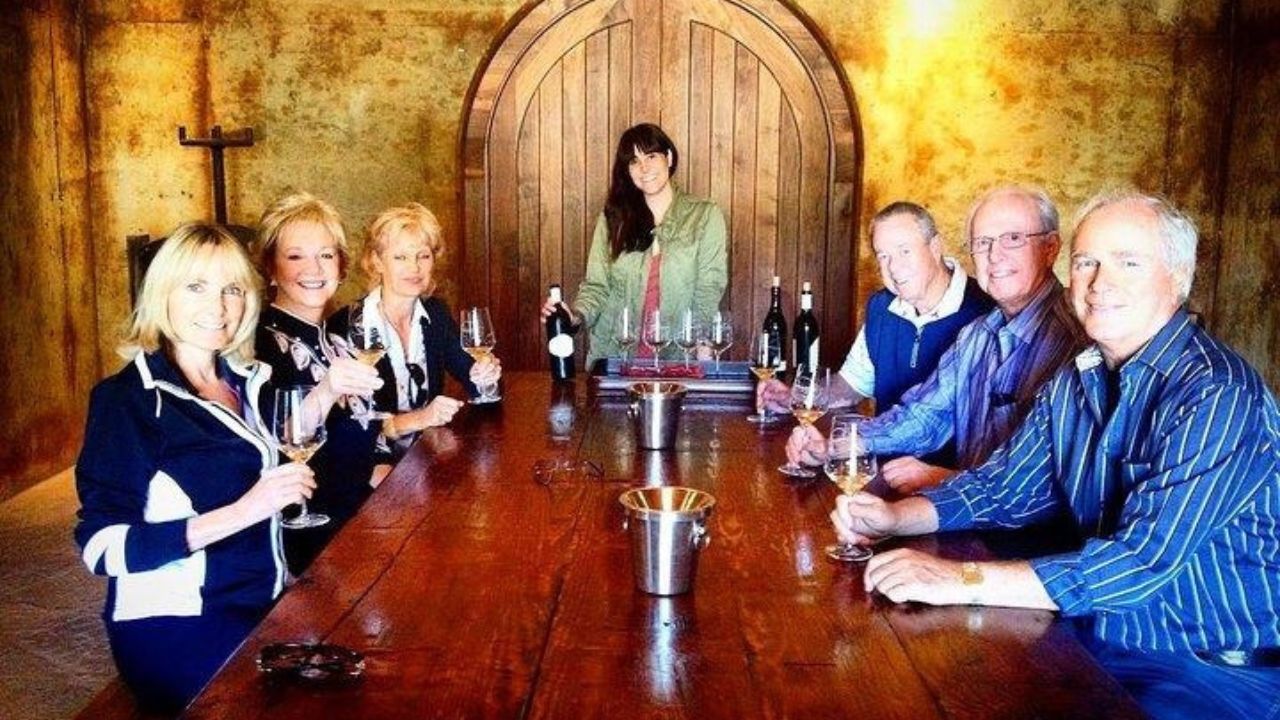 Group tasting wine in rustic boutique winery cellar setting.