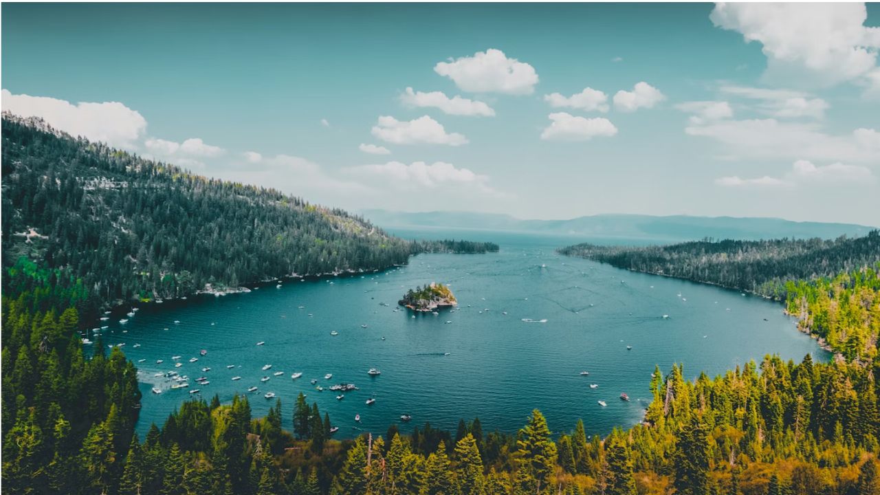 Lake Tahoe with boats, forested mountains, and island.