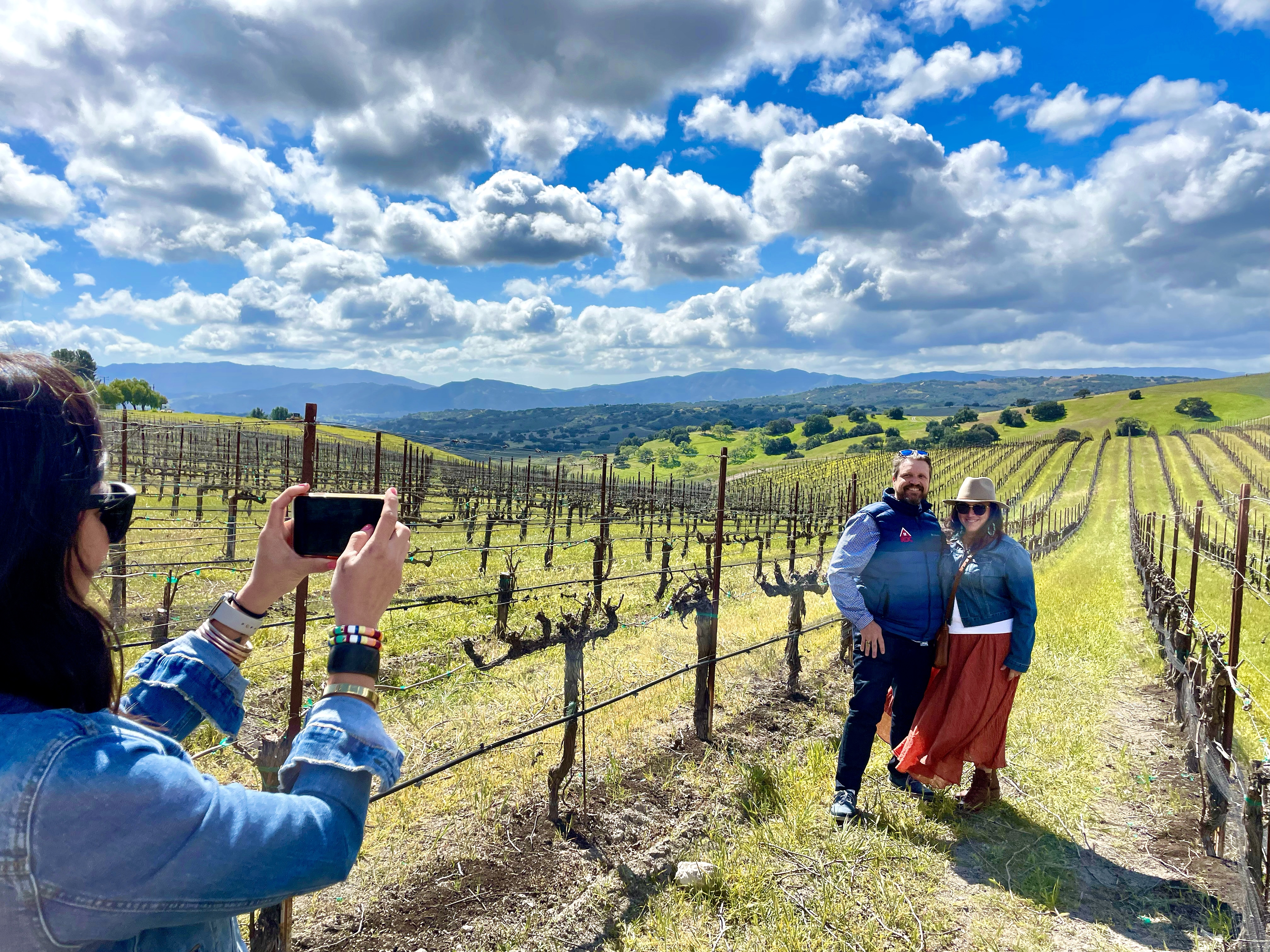 Couple enjoying vineyard wine tour in scenic countryside.