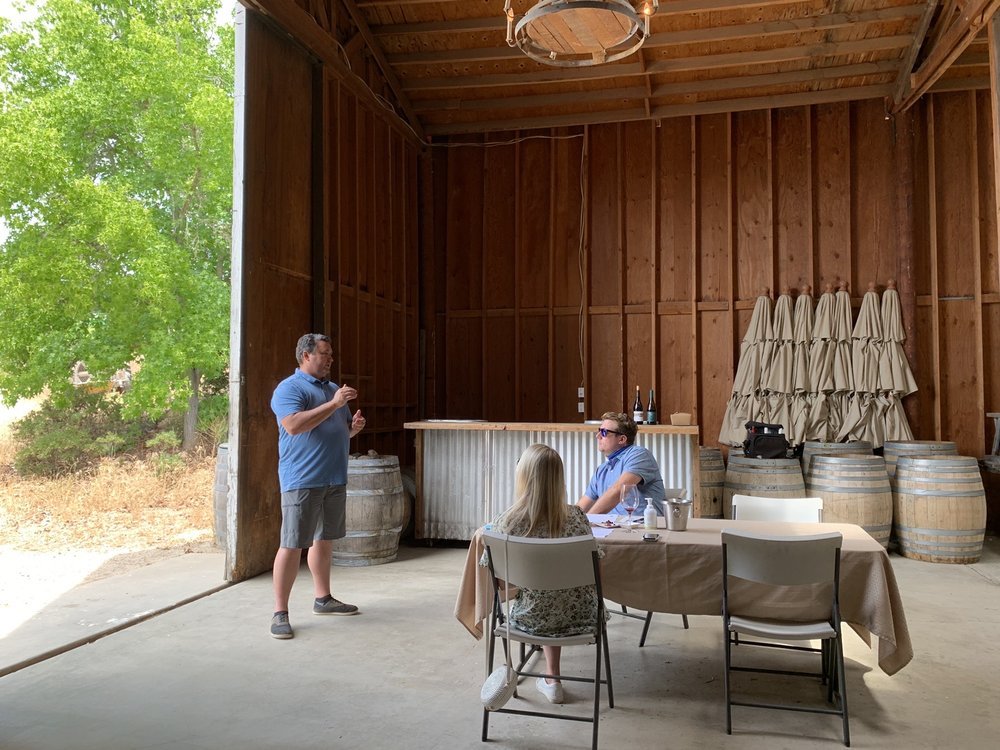 Santa Barbara tasting room with barrels and wine discussion.