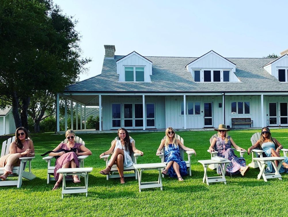 Women relaxing on lawn chairs during wine tour gathering.