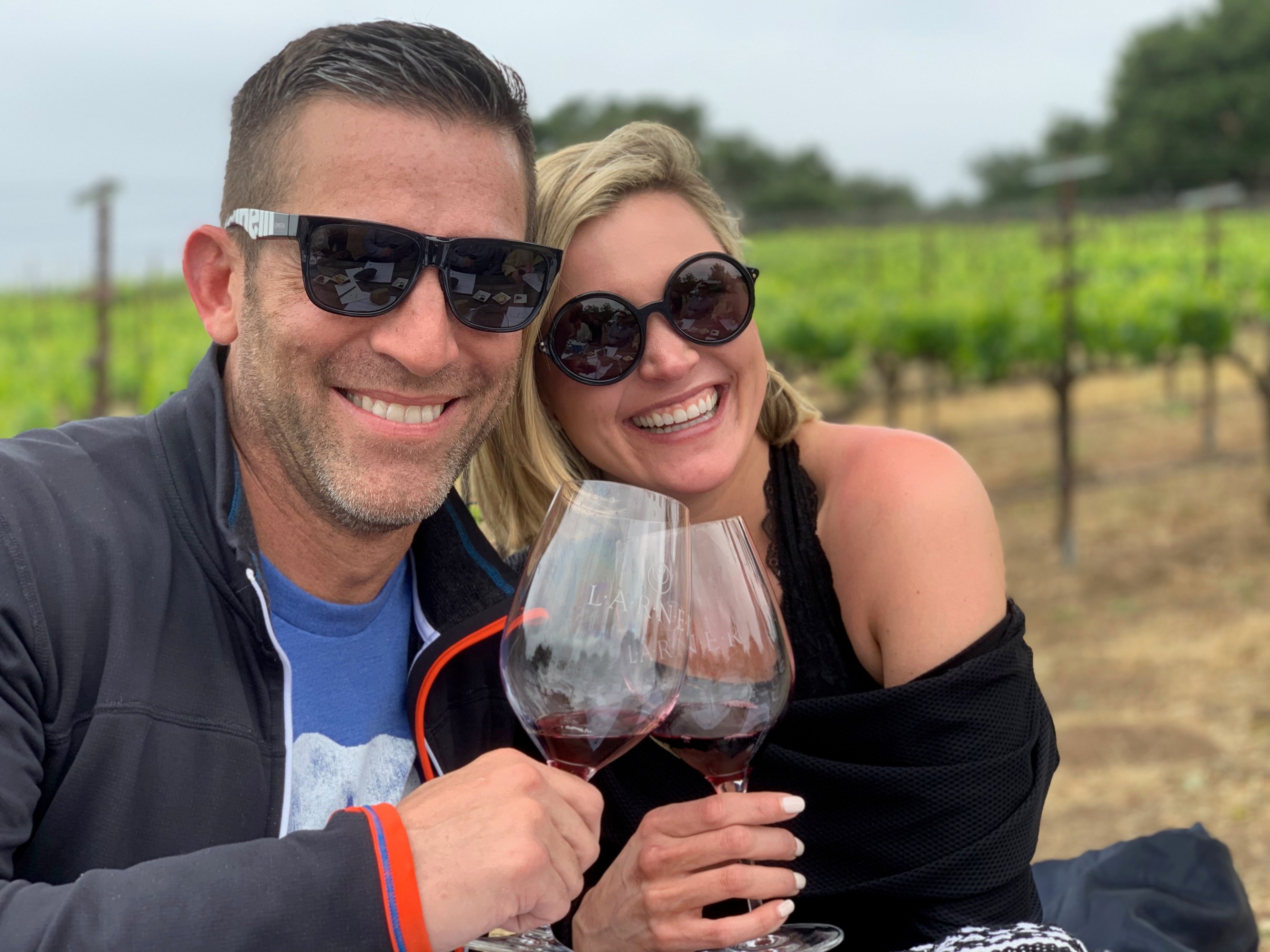 Couple enjoying wine tasting among vineyard rows during tour